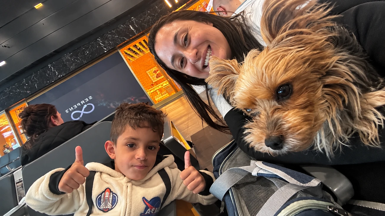 Mãe e filho sorrindo com seu cachorrinho na caixa de transporte de viagem aérea