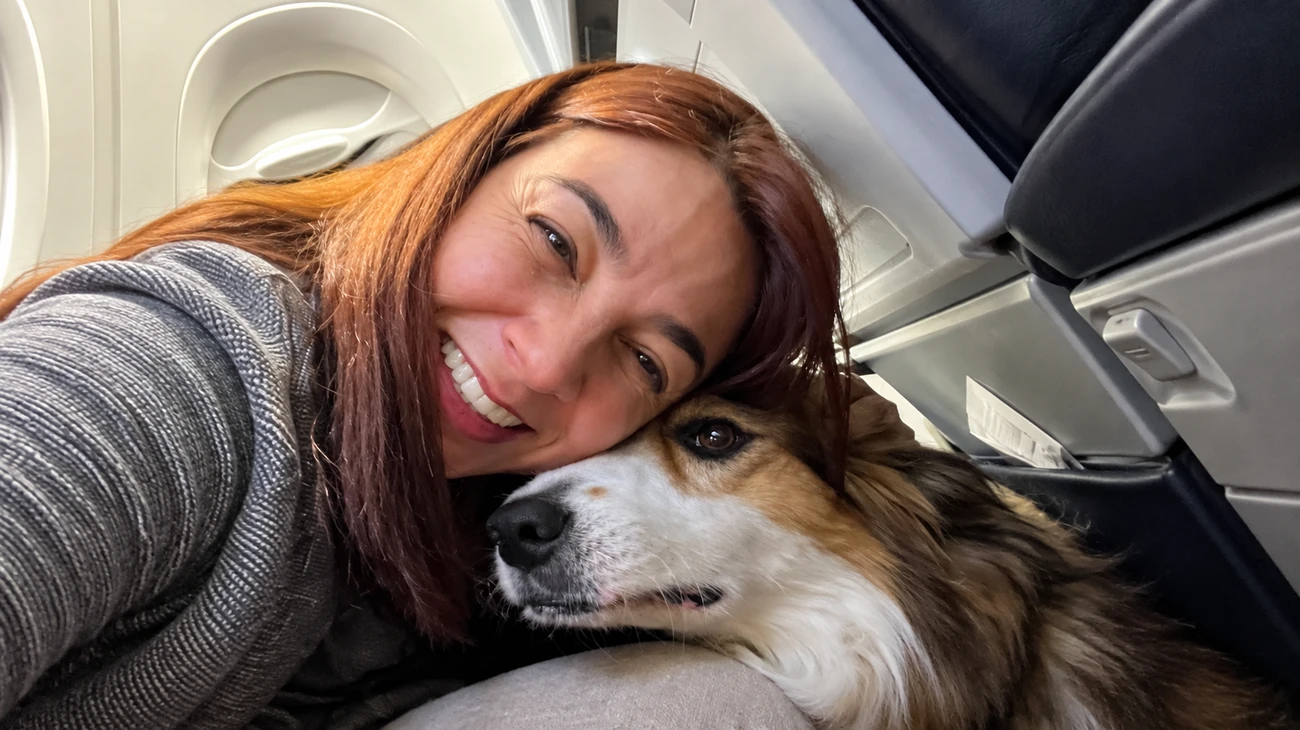Selfie de tutora sorridente com seu cão de pelo longo pronto para viajar com a Embarpet